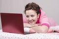 Cheerful girl in bed works for laptop Royalty Free Stock Photo