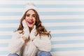 Cheerful girl with big beautiful eyes posing with excitement in funny knitted hat. Indoor portrait of magnificent female Royalty Free Stock Photo