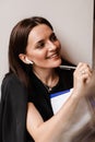 Cheerful girl with book in cafe. Concentrated English teacher writes notes before online lesson via video communication Royalty Free Stock Photo