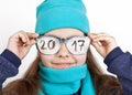 Cheerful girl in a cap and scarf in funny glasses with the inscription 2017