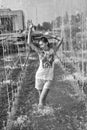 Cheerful girl dancing under jets of water in city fountain