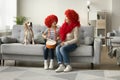 Cheerful girl and grandma in red wigs sitting with dog Royalty Free Stock Photo