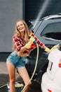 Girl holding pressure washer and smiling near autos Royalty Free Stock Photo
