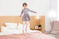 Cheerful girl jumping on bed