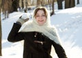 Cheerful girl in a knitted scarf winter throws snow Russian winter