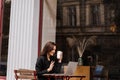 Cheerful girl with laptop and coffee have video chat with friends and family in cafe outdoor. Emotional woman is smiling Royalty Free Stock Photo