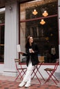 Cheerful girl with laptop standing near outside of cafe. Young woman is holding her laptop and smiling in cafe. Royalty Free Stock Photo