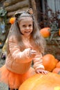 A cheerful girl leans on a large orange pumpkin and shows her thumb raised up. Autumn harvest