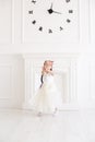 Vertical portrait of a five year old girl in a long white dress playing in a white studio Royalty Free Stock Photo