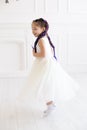 Vertical portrait of a five year old girl in a white dress who is having fun in a white studio Royalty Free Stock Photo