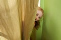 Cheerful girl looks out from behind curtains Royalty Free Stock Photo
