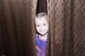 Cheerful girl looks out from behind the curtains Royalty Free Stock Photo