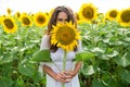 Cheerful girl looks out from sunflower in a field Royalty Free Stock Photo