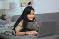 Cheerful girl lying on couch and surfing internet wit laptop computer. Royalty Free Stock Photo