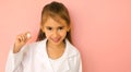 Cheerful girl portraying a doctor in a white medical coat holds a tooth