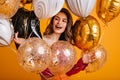 Cheerful girl preparing for party. Merry female model holding sparkle balloons