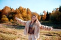 Cheerful girl with raised hands on the field in warm autumn season. Royalty Free Stock Photo