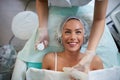 Cheerful girl is receiving facial treatment by beautician