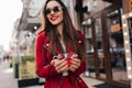 Cheerful girl with red manicure holding cup of tea. Portrait of spectacular brunette young lady in black sunglasses