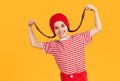 Cheerful girl in red outfit laughing merrily and holding on to her pigtails