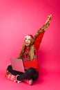 Cheerful girl in a red sweater and Santa hat, sitting with a lap Royalty Free Stock Photo