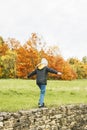 Cheerful girl schoolgirl walks in the park in nature in the autumn forest, balancing on a stone fence. Healthy family