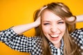 Cheerful girl in a shirt clutches her head with her hands laughing and looking at the camera