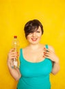 Cheerful girl with short hair with a big bottle of water on a yellow background in the Studio Royalty Free Stock Photo