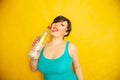 Cheerful girl with short hair with a big bottle of water on a yellow background in the Studio Royalty Free Stock Photo