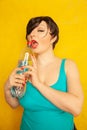 Cheerful girl with short hair with a big bottle of water on a yellow background in the Studio Royalty Free Stock Photo