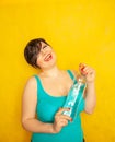 Cheerful girl with short hair with a big bottle of water on a yellow background in the Studio Royalty Free Stock Photo