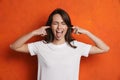 Cheerful girl showing her tongue while plugging her ears Royalty Free Stock Photo