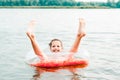 Cheerful girl sits in an inflatable ring with sticking legs in the river. Local tourism