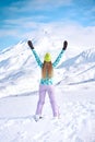 Cheerful girl snowboarder in blue sweater in front of snowy mountains