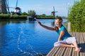 Cheerful girl  tourist splashing in the river on the beautiful landscape backgorund with old windmills in Netherlands Royalty Free Stock Photo