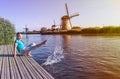 Cheerful girl  tourist splashing in the river on the beautiful landscape backgorund with old windmills in Netherlands Royalty Free Stock Photo