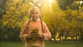 Cheerful girl with yellow leaves looking at camera, childish mood, autumn park