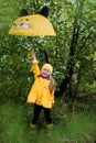 Cheerful girl in a yellow raincoat, a yellow hat with a yellow umbrella on a sunny spring day Royalty Free Stock Photo