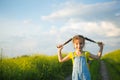 Cheerful girl in a yellow summer field smiles and holds himself by the braids. Joy, sunny weather, holidays.Repellent for Royalty Free Stock Photo