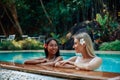 Cheerful girls in bikini swim in pool and enjoy journay in Thailand