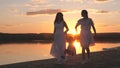cheerful girls with small child are walking along the summer beach at sunset, happy family, raising a child together Royalty Free Stock Photo