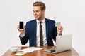 Cheerful, glad stylish and successful male entrepreneur in business suit sitting near laptop, coffee cup and documents Royalty Free Stock Photo