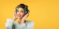 Cheerful Glamorous Lady With Hair Curlers Touching Hair, Yellow Background