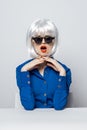 cheerful glamorous Woman in a White wig sits at the table with emotion blue shirt