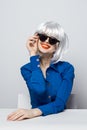 cheerful glamorous Woman in a White wig sits at the table with emotion blue shirt