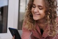 Cheerful gorgeous young woman with curly hair with smartphone