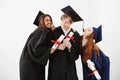 Cheerful graduate classmates celebrating smiling rejoicing over white background.