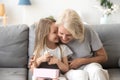 Cheerful grandma and grandchild sitting laughing together on couch