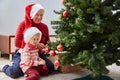 cheerful grandmother and her cute granddaughter girl decorate the Christmas tree. A grandmother and a small child are Royalty Free Stock Photo