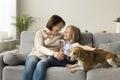 Cheerful granny and little granddaughter stroking cute dog, sitting close